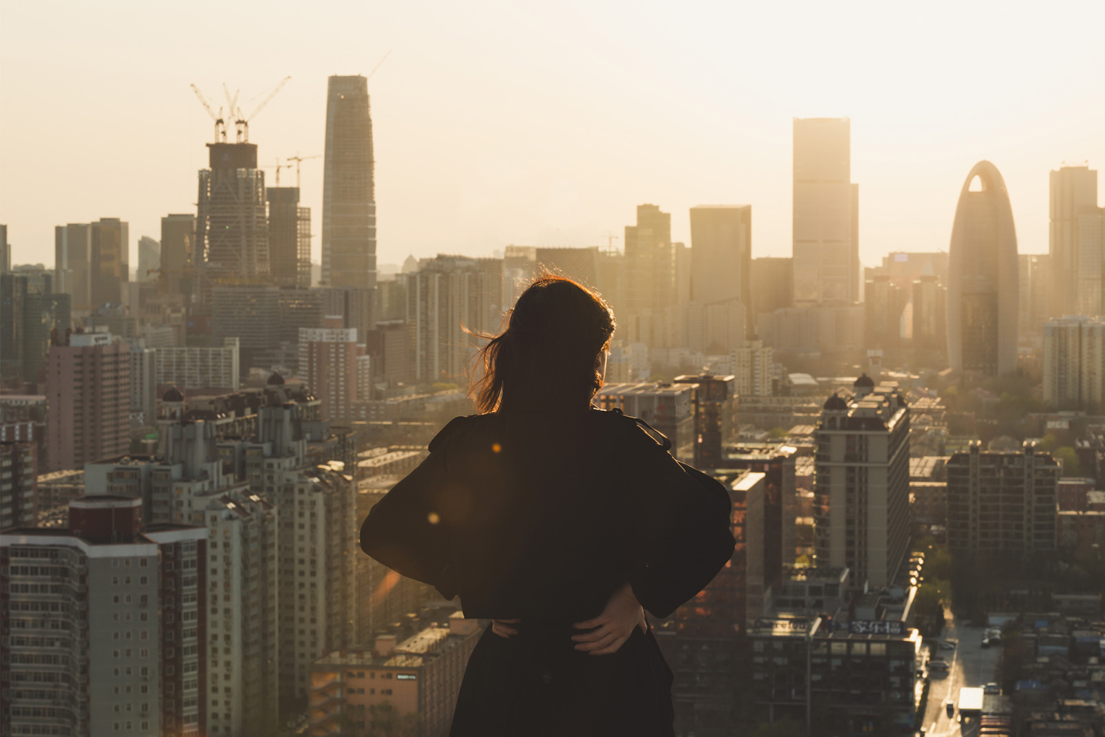 Business woman stares at city skyline from roof
