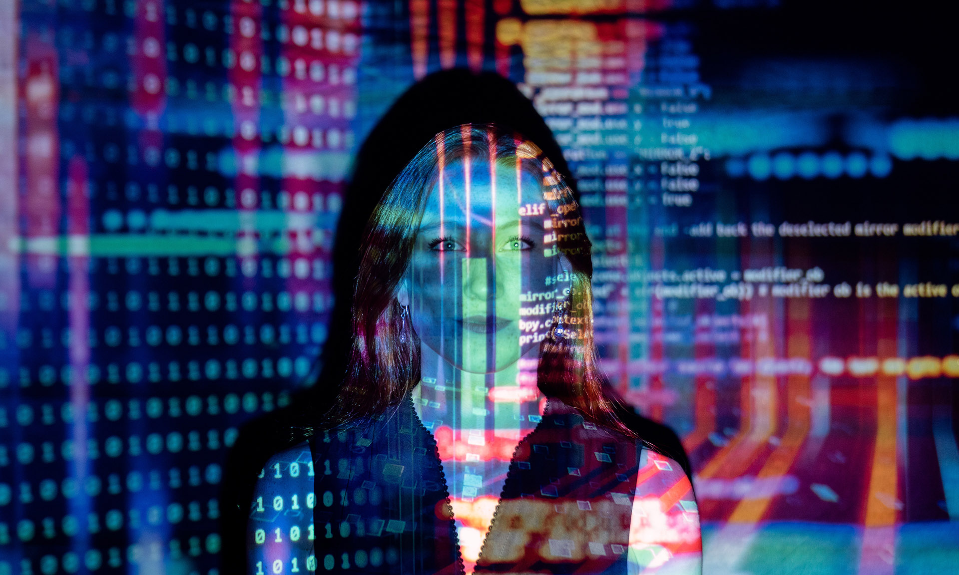 Young professional woman with computer code projected over her face and torso.